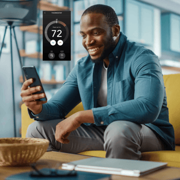 person sitting on couch changing the temperature of their home from their phone
