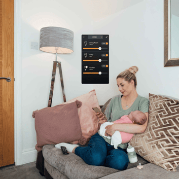 person holding a baby adjusting lighting form their phone